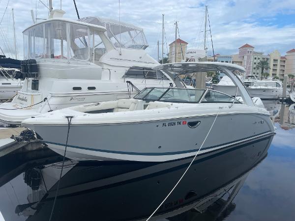 Cobalt 30SC 2022 Cobalt 30SC boat docked in marina, sleek white design, calm water reflection.