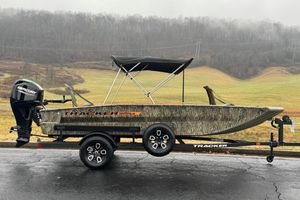 Tracker Grizzly 1756 T Marsh 2026 Tracker Grizzly 1756 T Marsh boat on trailer, camo design, Mercury engine, outdoor setting.