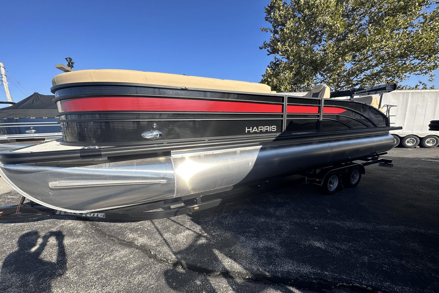 Harris Sunliner 250 2023 Harris Sunliner 250 pontoon boat on trailer, black and red design, outdoor setting.