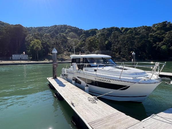 Jeanneau NC Weekender 1095 2019 Jeanneau NC Weekender 1095 docked on a sunny day, surrounded by lush greenery.