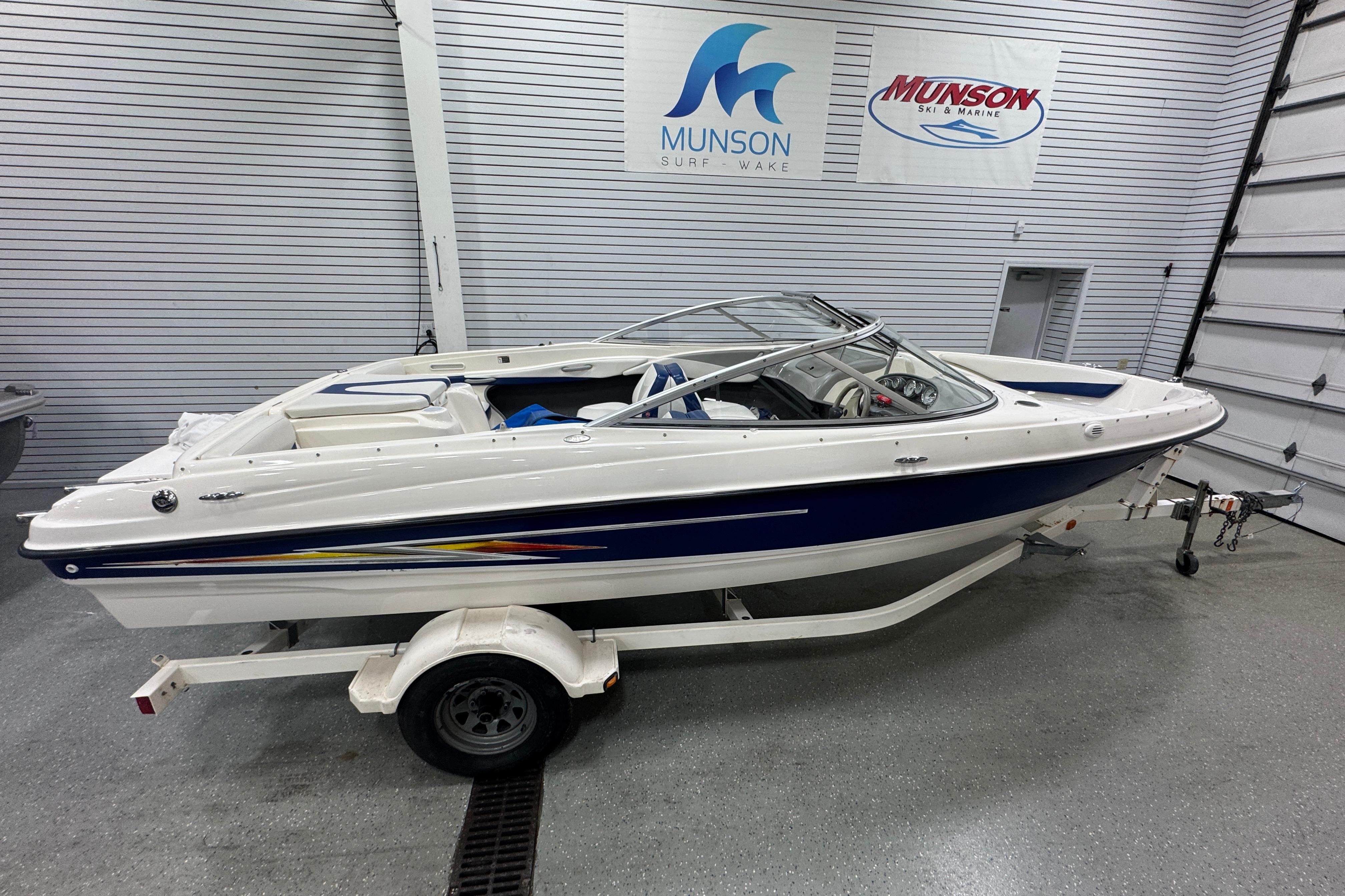 Bayliner 205 BR 2005 Bayliner 205 BR boat in showroom, white and blue design, on trailer.