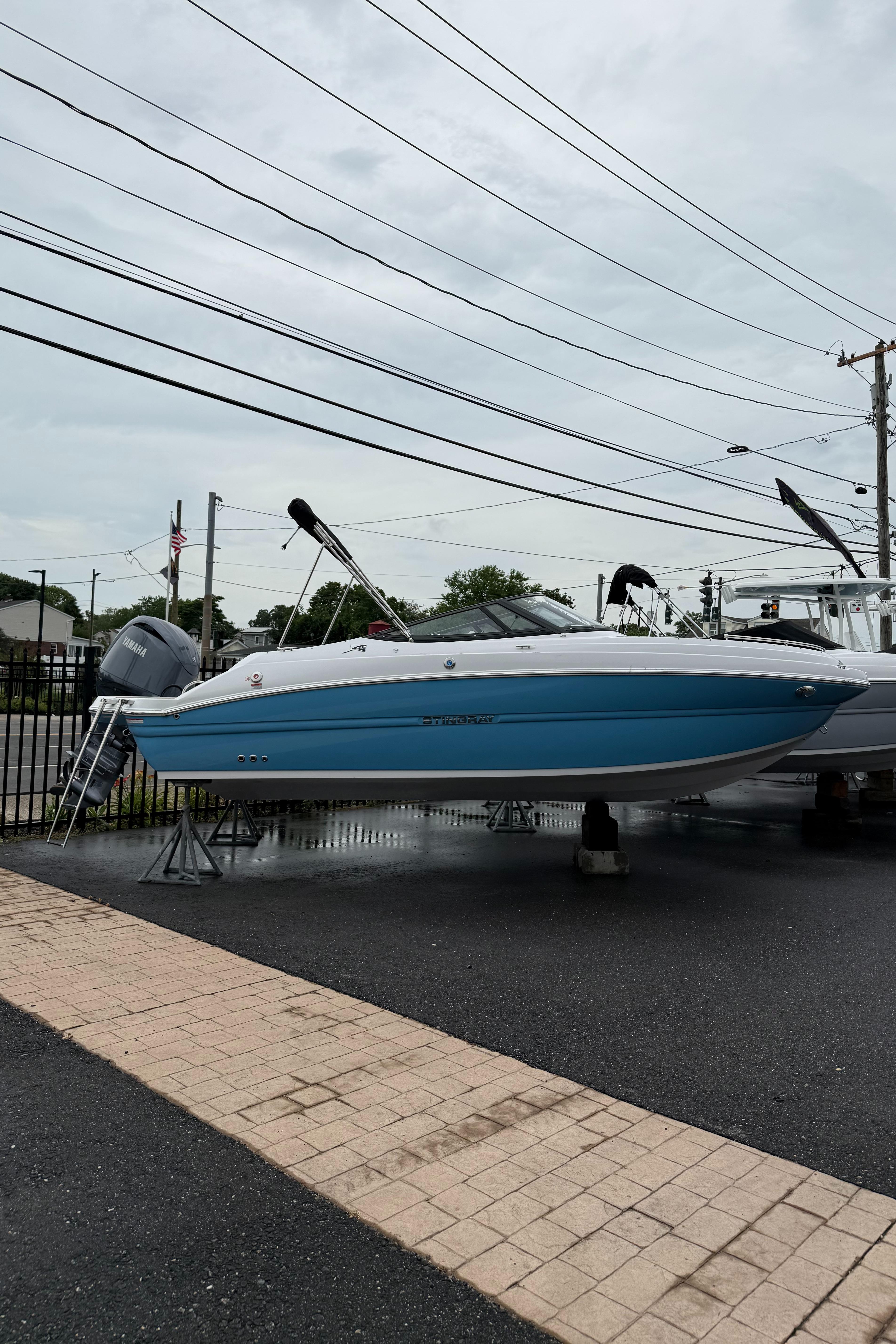 Stingray 211 DC 2025 Stingray 211 DC boat displayed on stands in a parking lot.