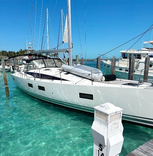 Jeanneau 54 2021 Jeanneau 54 yacht docked in clear turquoise water at a marina.