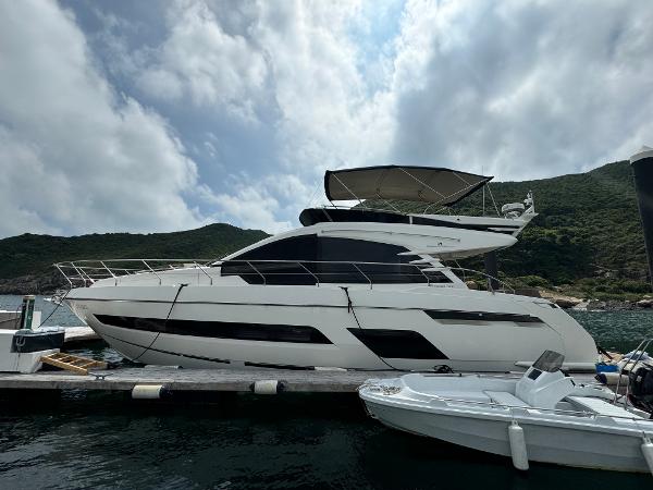 Fairline Squadron 53 2018 Fairline Squadron 53 yacht docked by scenic coastline under cloudy sky.