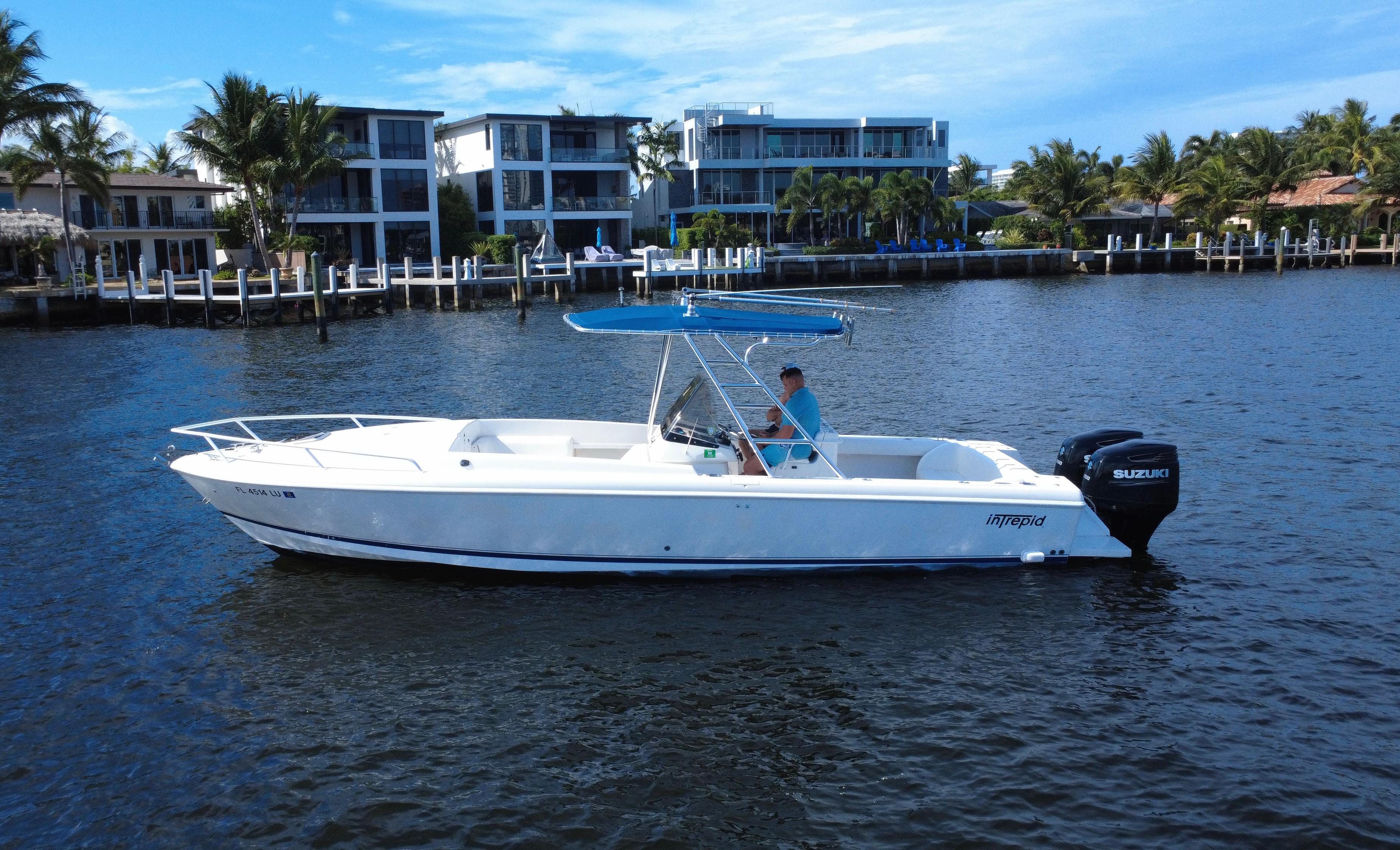 Intrepid 323 Cuddy 2002 Intrepid 323 Cuddy boat on water, with modern waterfront homes in the background.