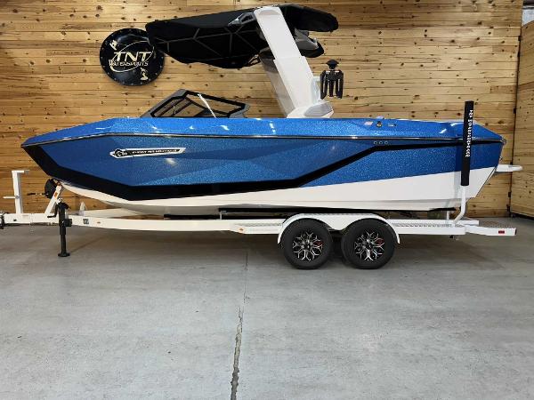 Nautique G23 2025 Nautique G23 boat in blue on a trailer, displayed indoors.