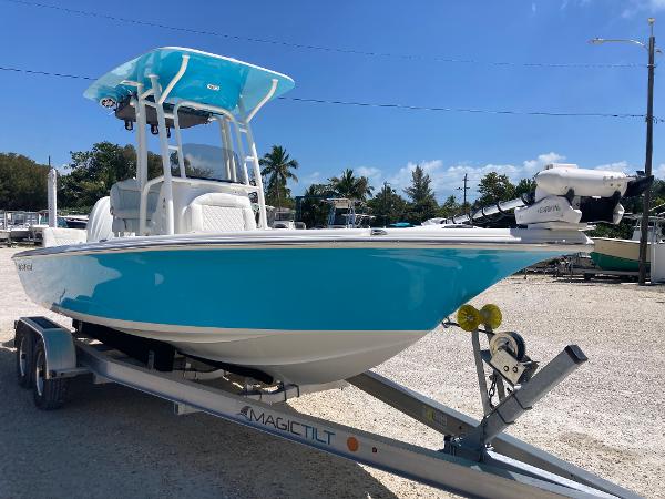 Key West 230 Bay Reef 2025 Key West 230BR boat on trailer, vibrant blue and white design, sunny outdoor setting.