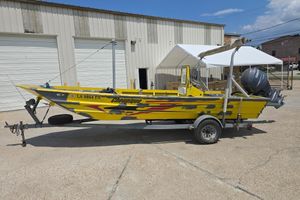 Custom 22 Yellow Rookie 22 boat from 2006 on trailer, parked outside a garage.