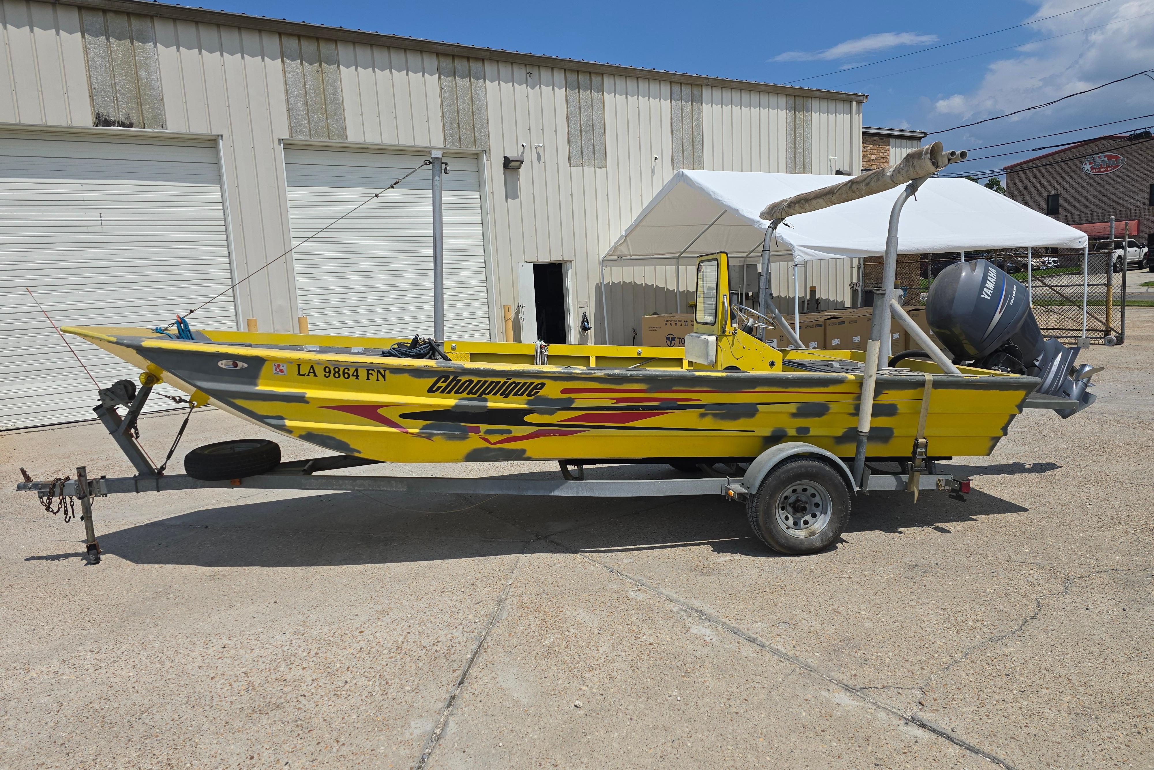 Custom 22 Yellow Rookie 22 boat from 2006 on trailer, parked outside a garage.