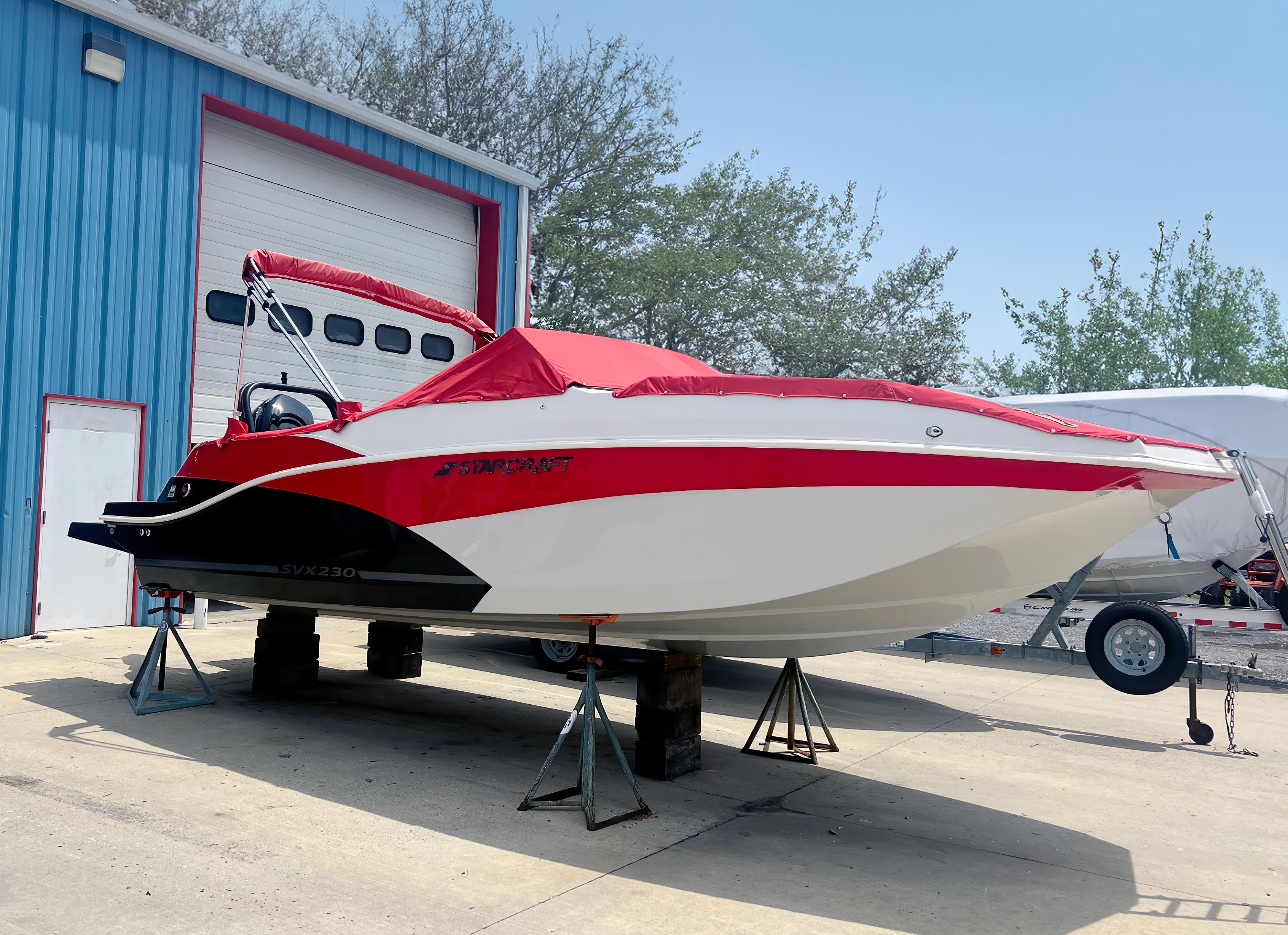 Starcraft SVX 230 OB 2024 Starcraft SVX 230 OB boat with red cover, displayed outdoors.