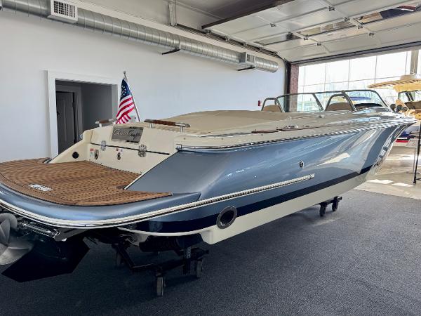 Chris-Craft Launch 27 2025 Chris-Craft Launch 27 boat in showroom, featuring sleek design and American flag.