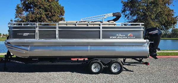 Sun Tracker Fishin' Barge 20 DLX 2025 Sun Tracker Fishin' Barge 20 DLX pontoon boat on trailer, parked outdoors.