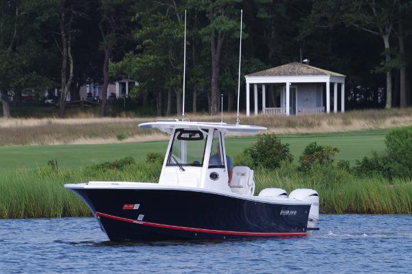 Regulator 28 2024 Regulator 28 boat cruising on a serene lake near a gazebo.