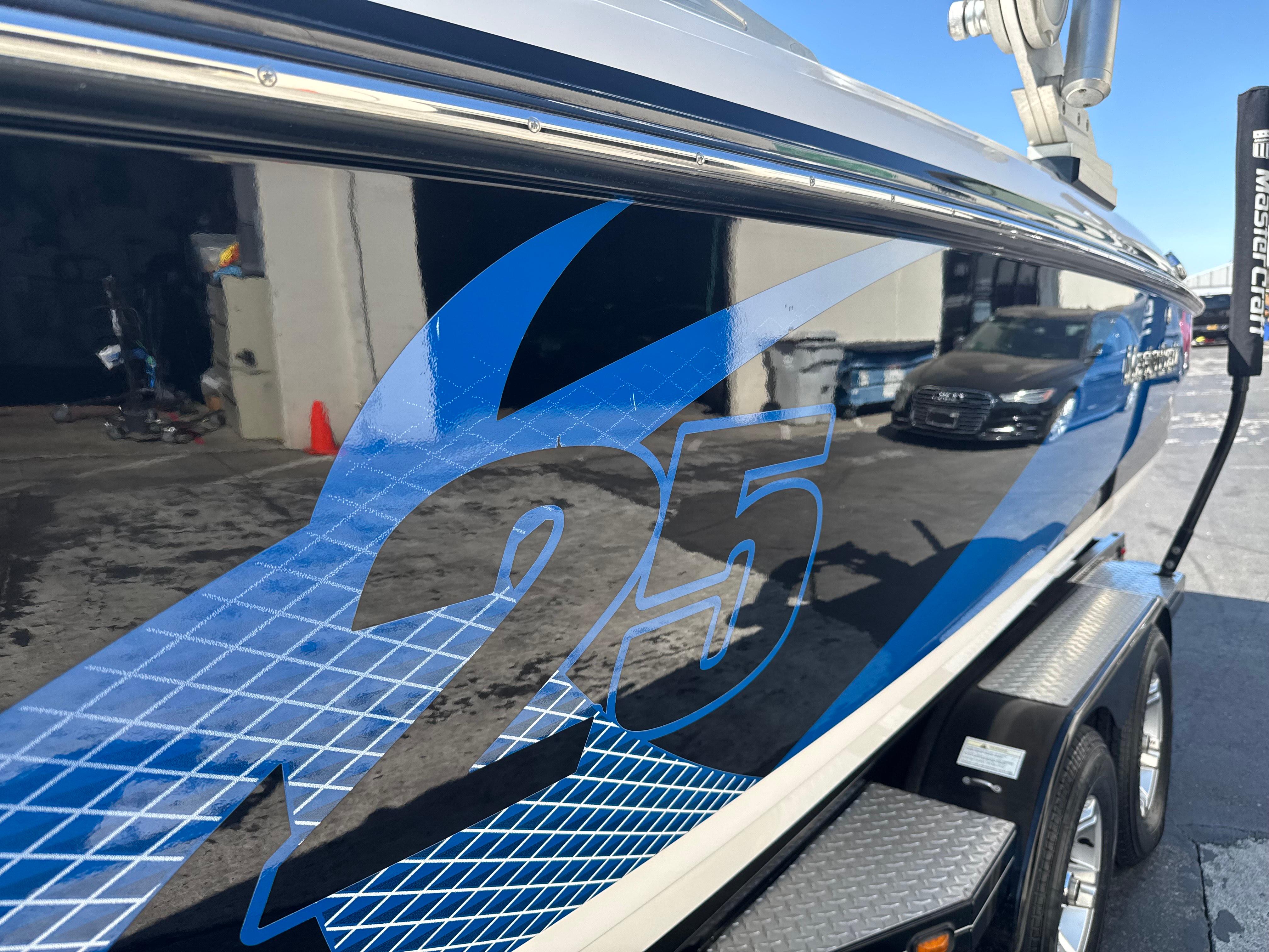 MasterCraft X-25 2012 MasterCraft X-25 boat with blue graphics, parked on a trailer.