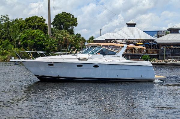 Tiara Yachts 3500 Express 2000 Tiara Yachts 3500 Express cruising on a calm river near a waterfront building.