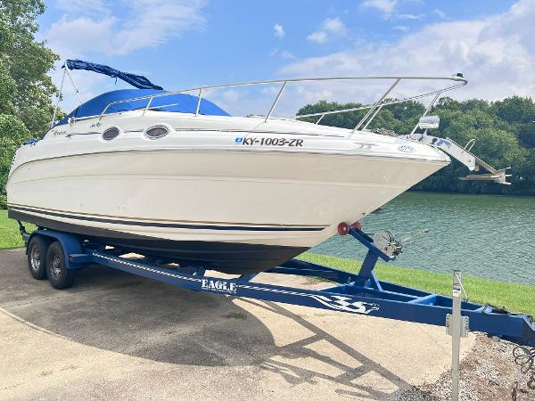 Sea Ray 260 Sundancer 2001 Sea Ray 260 Sundancer boat on trailer by a lake, under a clear sky.