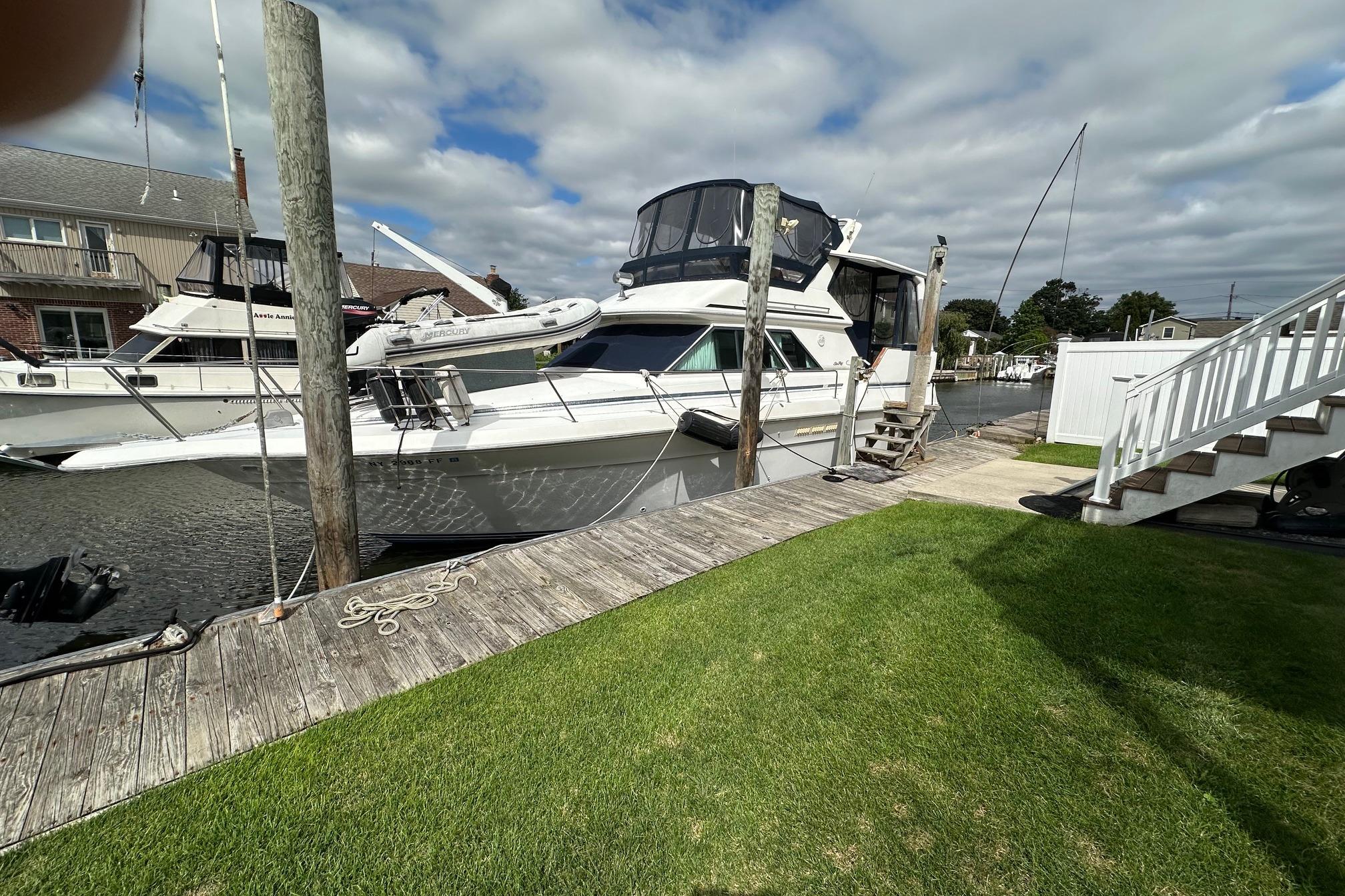 Sea Ray 380 Aft Cabin 1989 Sea Ray 380 Aft Cabin yacht docked by a wooden pier under cloudy skies.