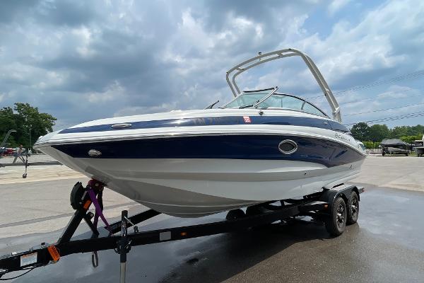 Crownline E235 2023 Crownline E235 boat on trailer under cloudy sky.