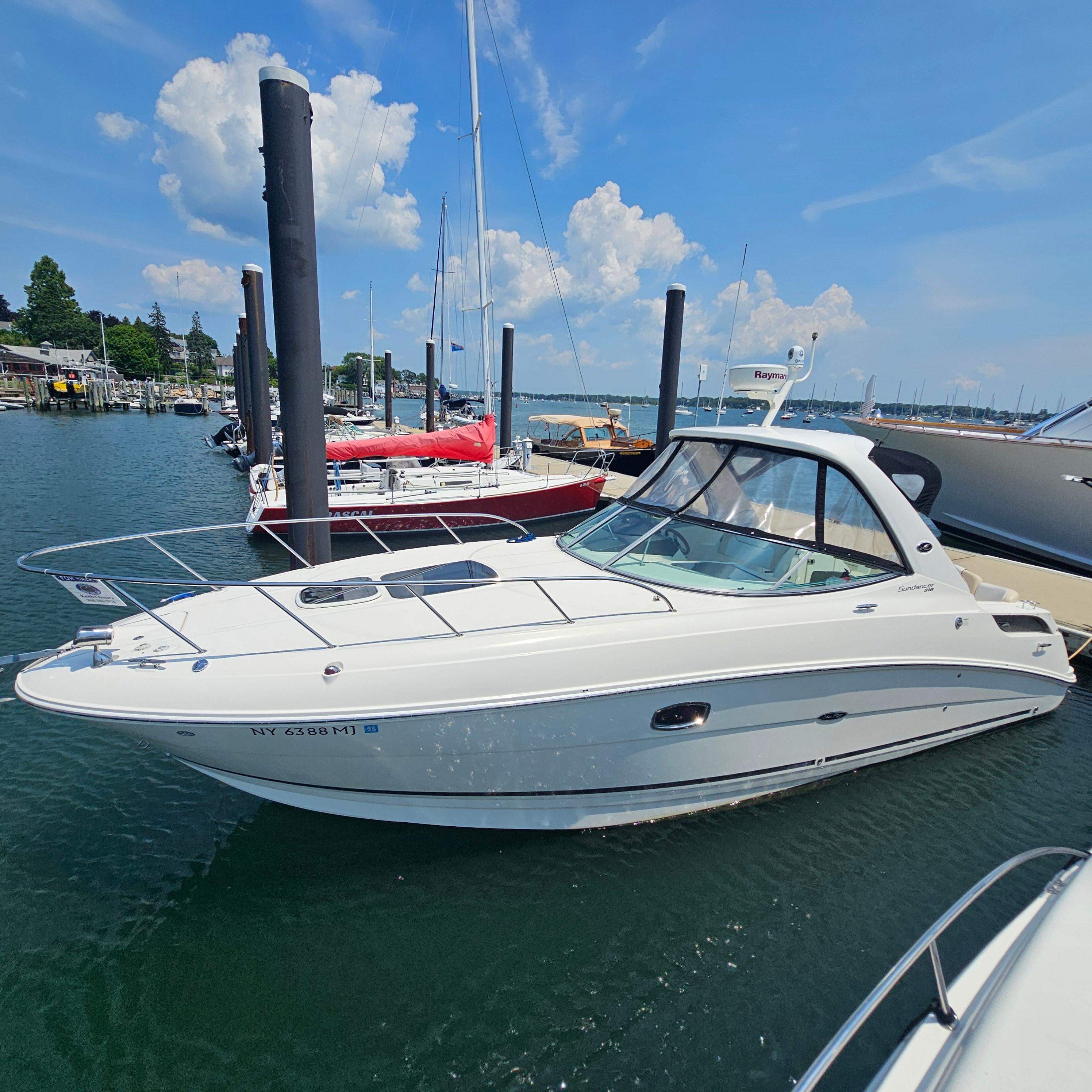 Sea Ray 310 Sundancer 2013 Sea Ray 310 Sundancer docked in a marina under a clear blue sky.