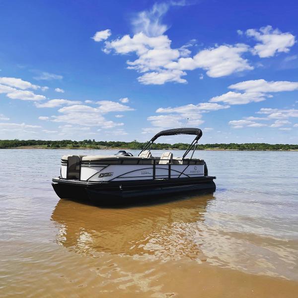 Regency 230 DL3 2021 Regency 230 DL3 pontoon boat on calm lake under blue sky.