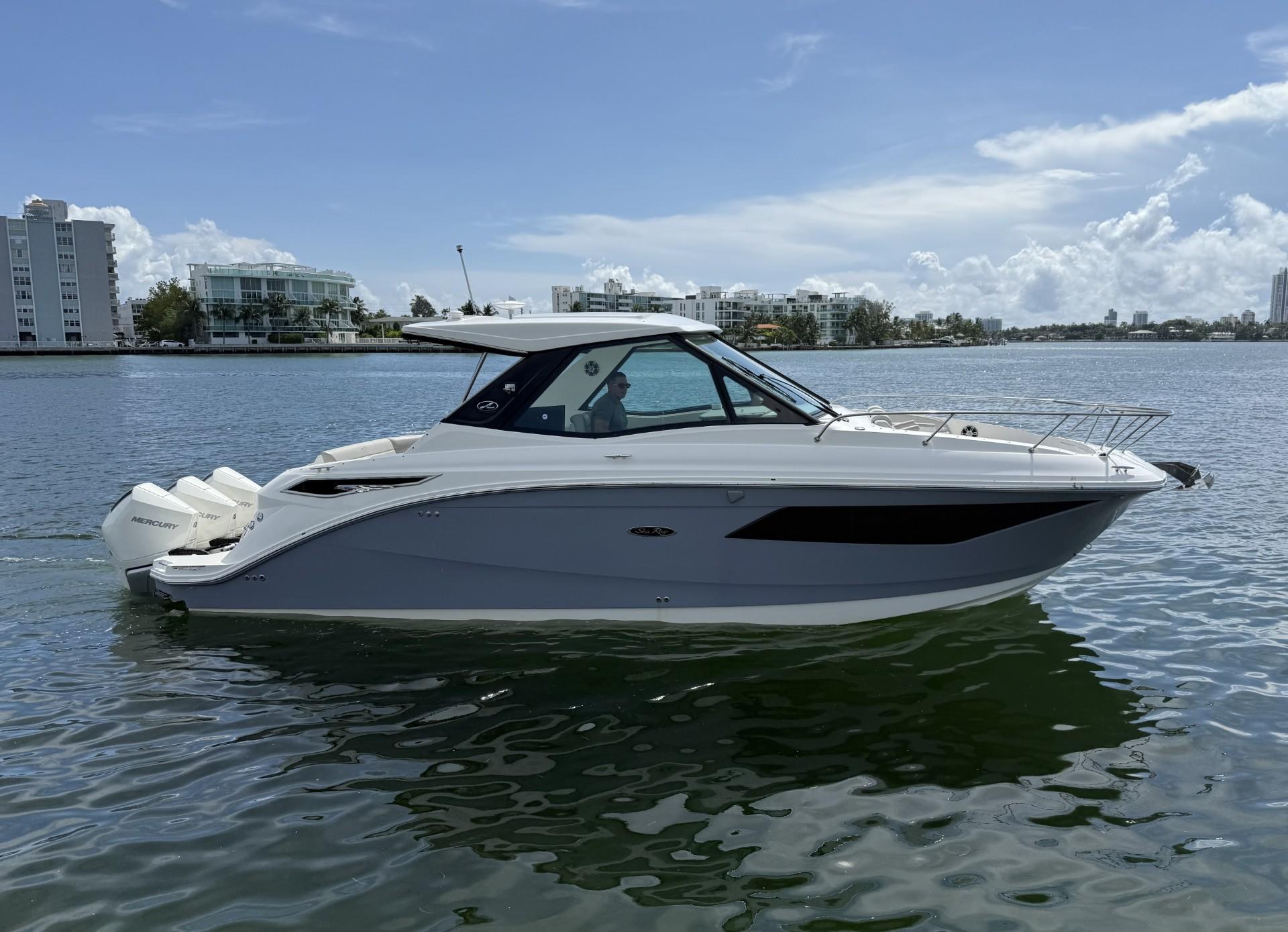 Sea Ray Sundancer 320 Outboard 2024 Sea Ray Sundancer 320 Outboard cruising on calm waters, cityscape in background.