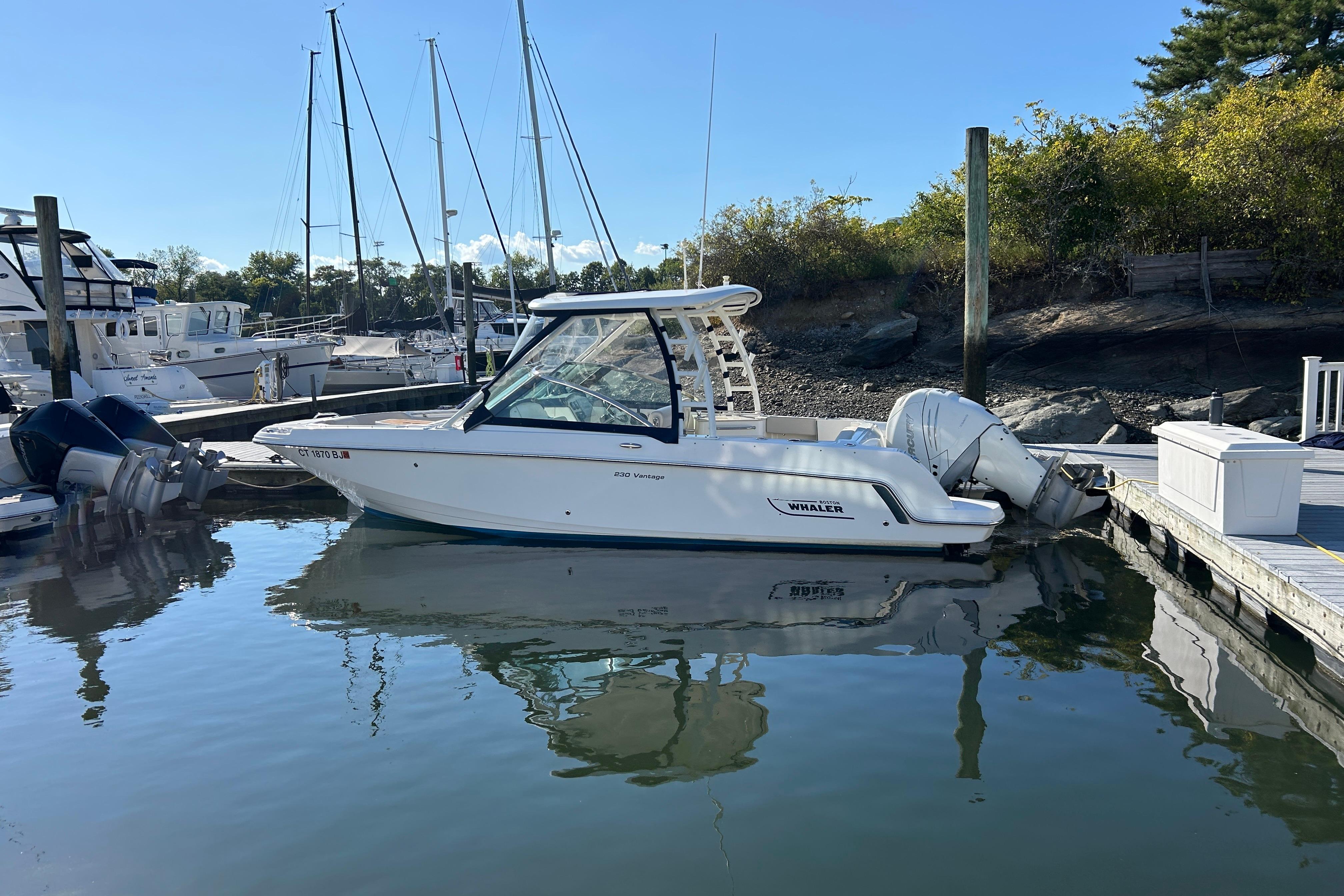 Boston Whaler 230 Vantage 2016 Boston Whaler 230 Vantage boat docked in a marina, surrounded by calm water.