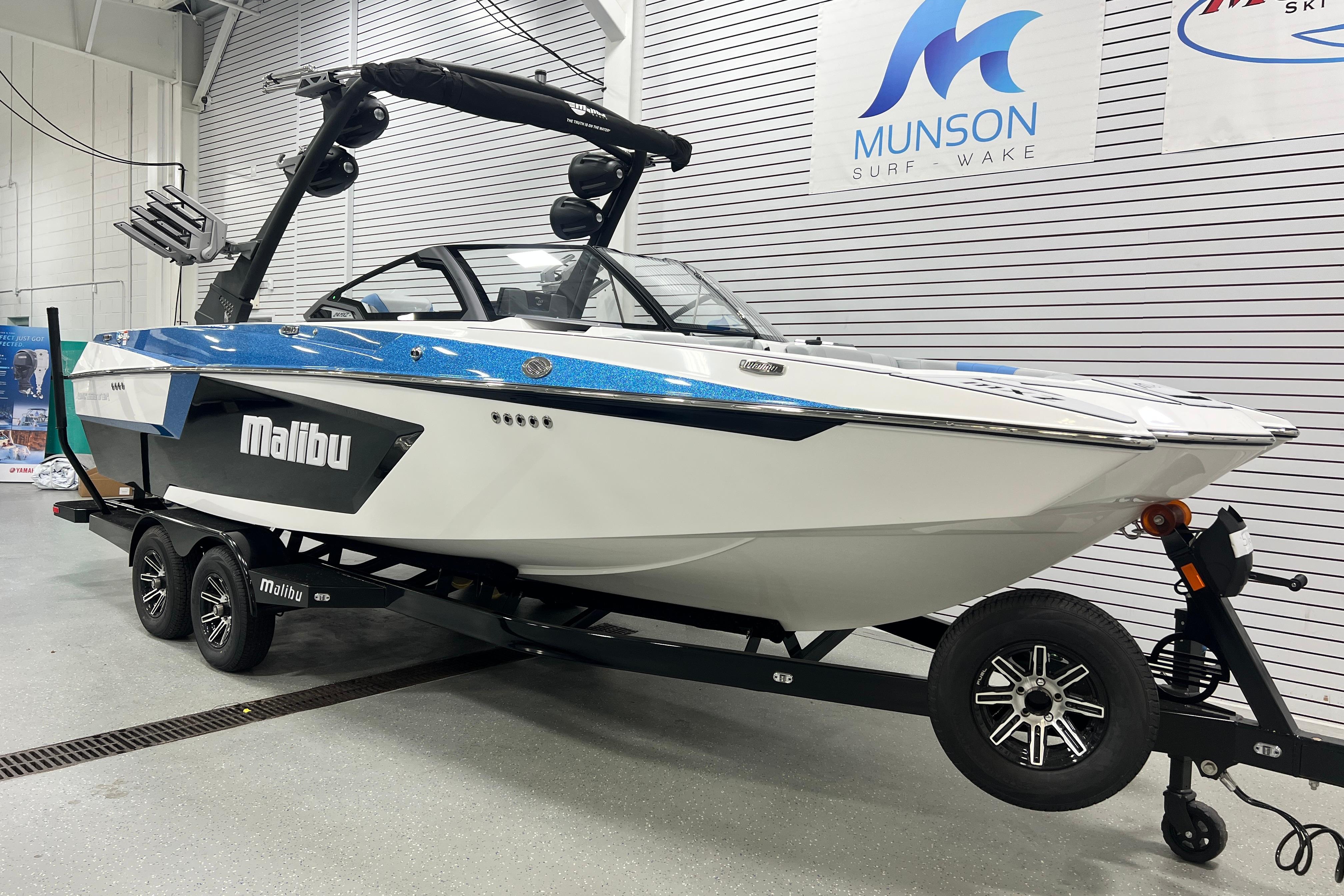 Malibu Wakesetter 24 MXZ 2024 Malibu Wakesetter 24 MXZ boat on trailer in showroom.