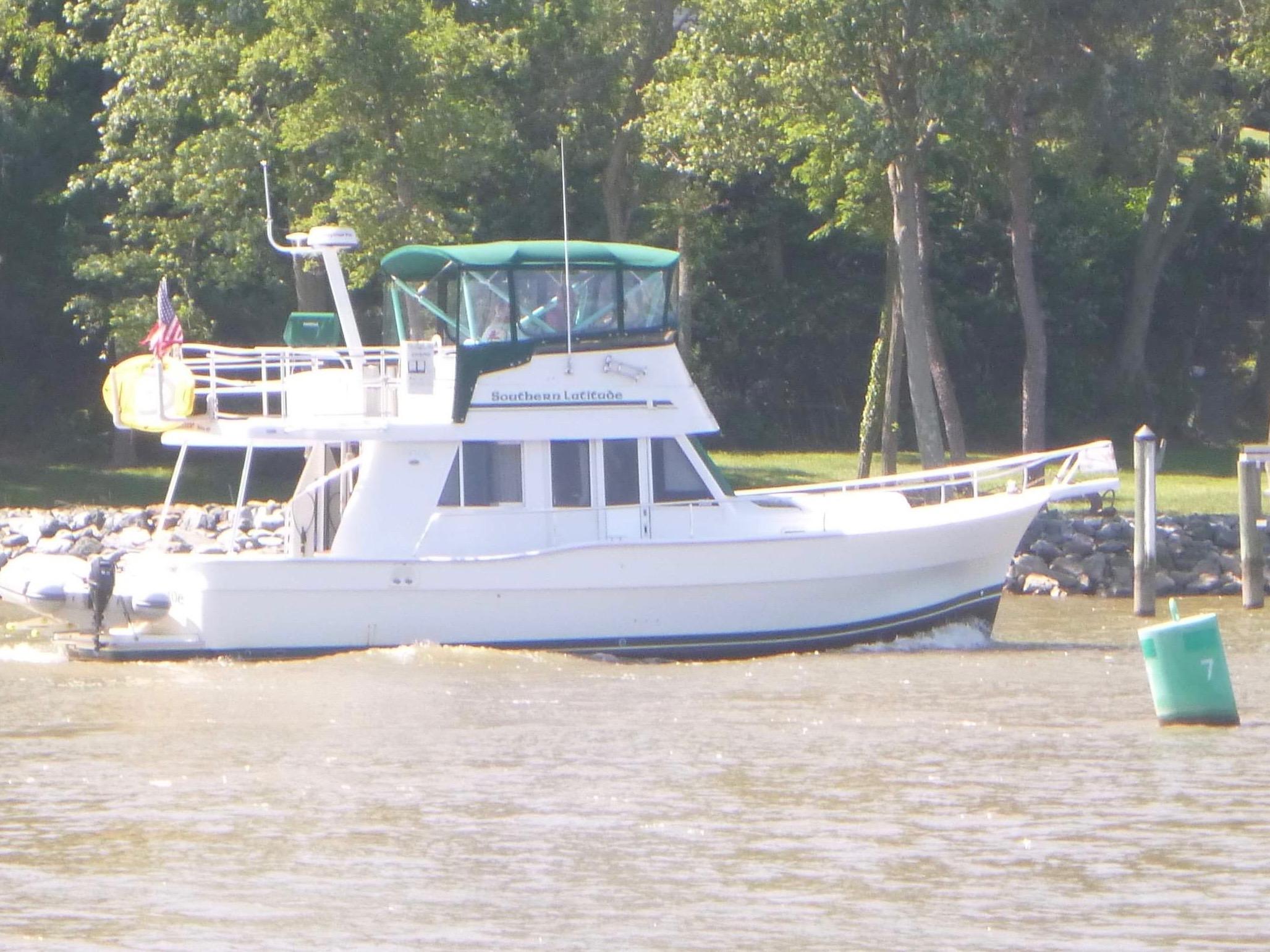 Mainship 390 Trawler 2000 Mainship 390 Trawler cruising on a river near a wooded shoreline.