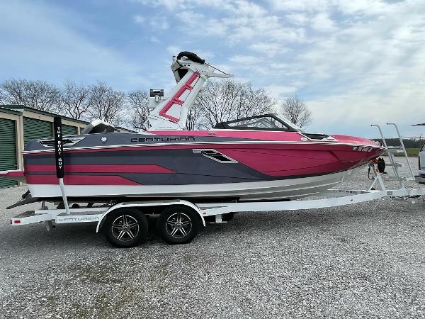 Centurion Ri230 2022 Centurion Ri230 boat in pink and gray on a trailer, parked outdoors.
