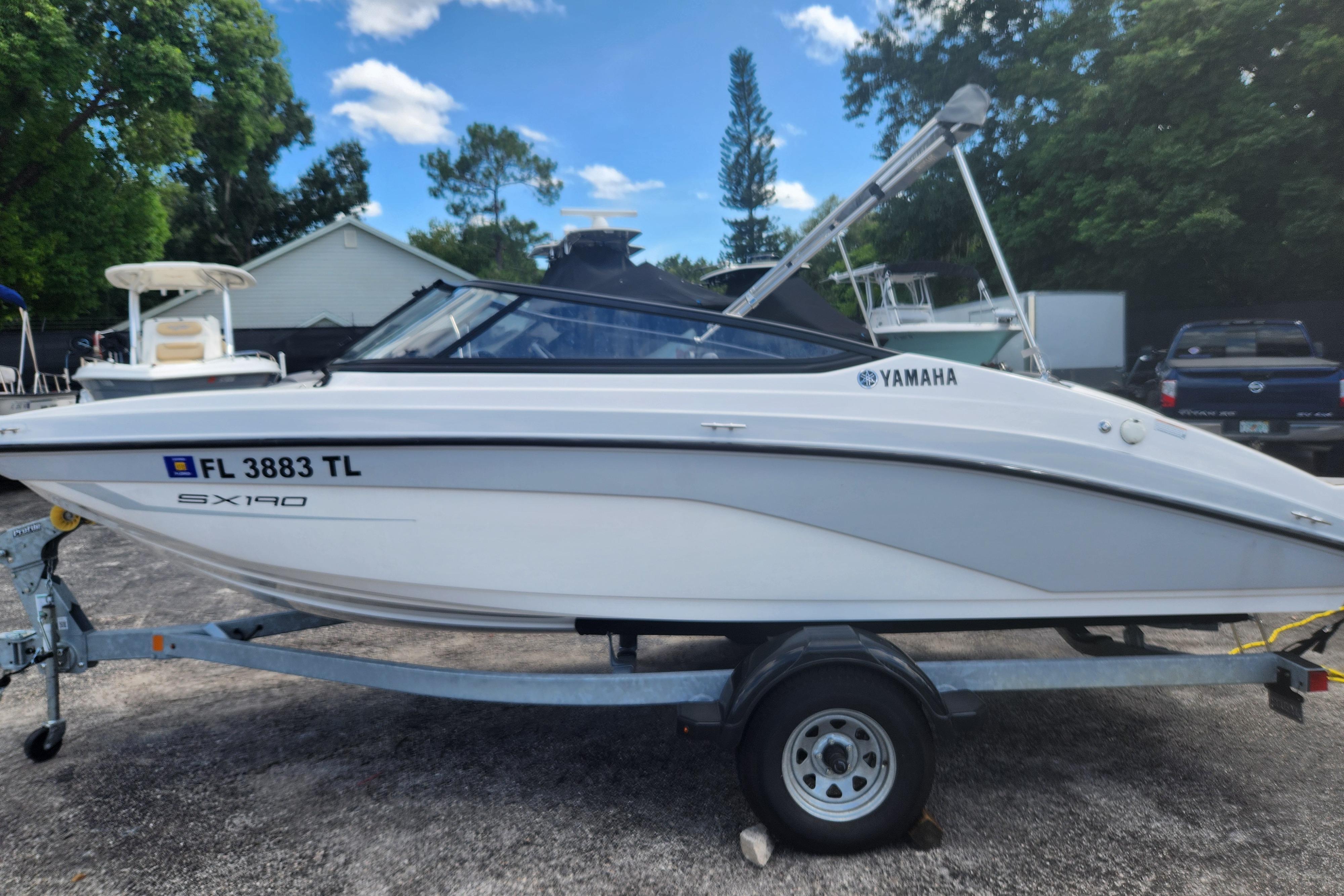 Yamaha Boats SX190 2023 Yamaha SX190 boat on trailer, parked outdoors with trees and blue sky.