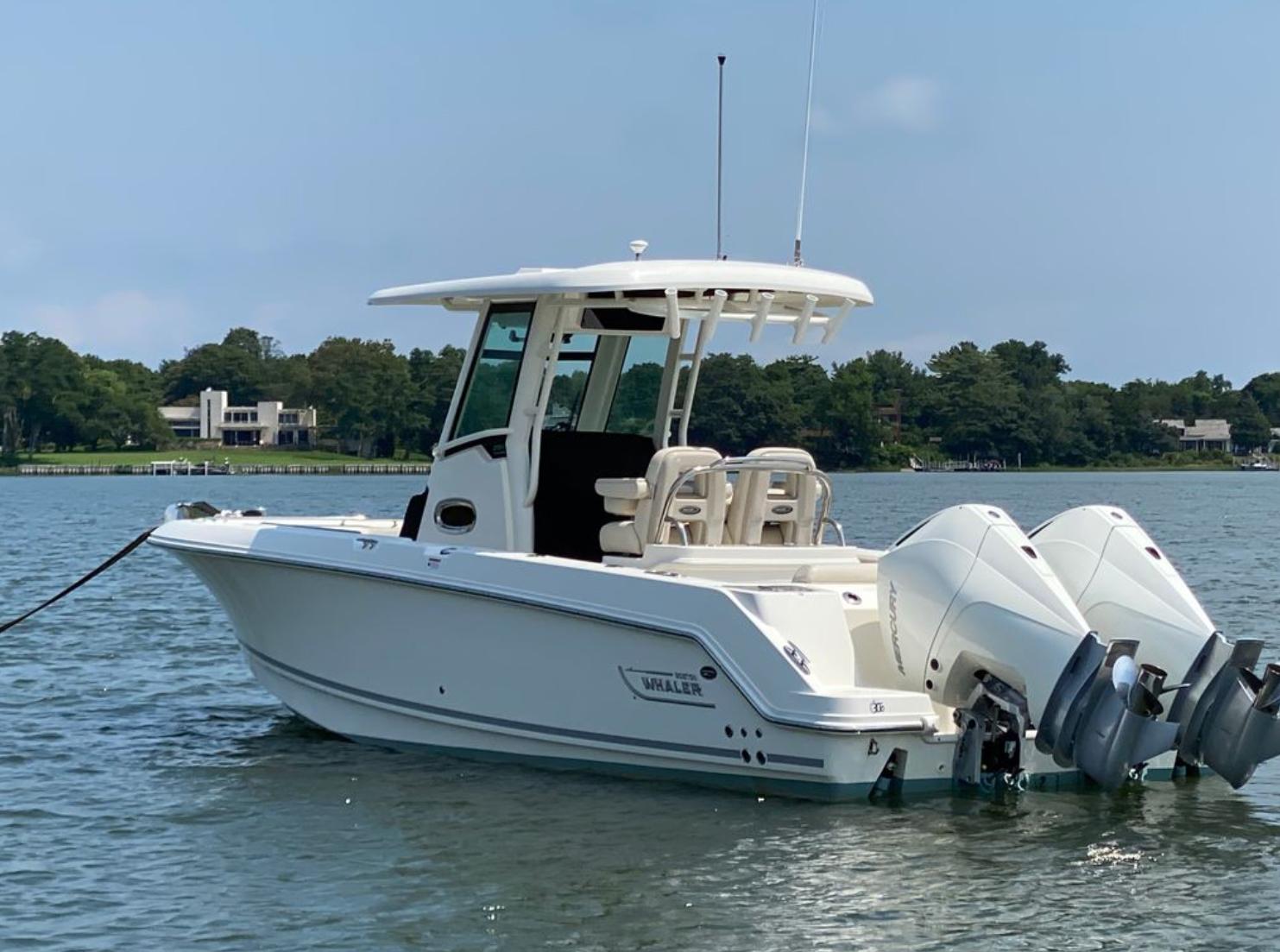 Boston Whaler 250 Outrage 2020 Boston Whaler 250 R boat with dual engines on a calm lake.