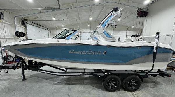 MasterCraft X24 2024 MasterCraft X24 boat in a garage, blue and white design on trailer.