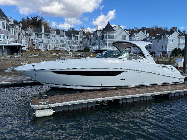Sea Ray 370 Sundancer 2016 Sea Ray 370 Sundancer docked near waterfront homes under a partly cloudy sky.