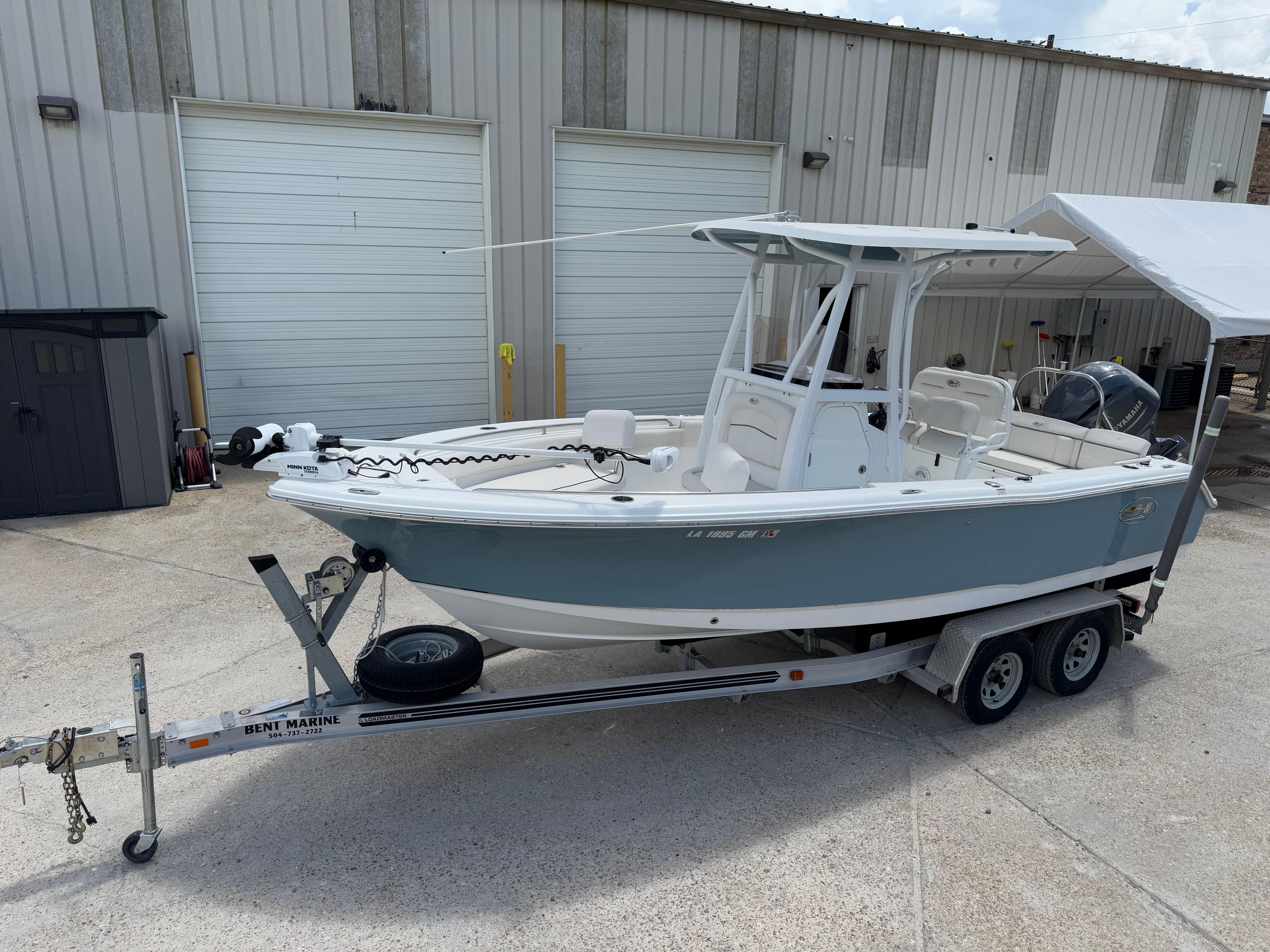 Sea Hunt Ultra 219 2021 Sea Hunt Ultra 219 boat on trailer, parked outside a warehouse.
