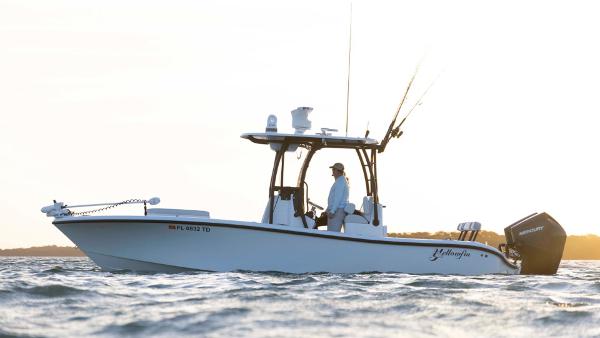 Yellowfin 26 Hybrid 2025 Yellowfin 26 Hybrid boat on water at sunset, featuring fishing rods and outboard motor.