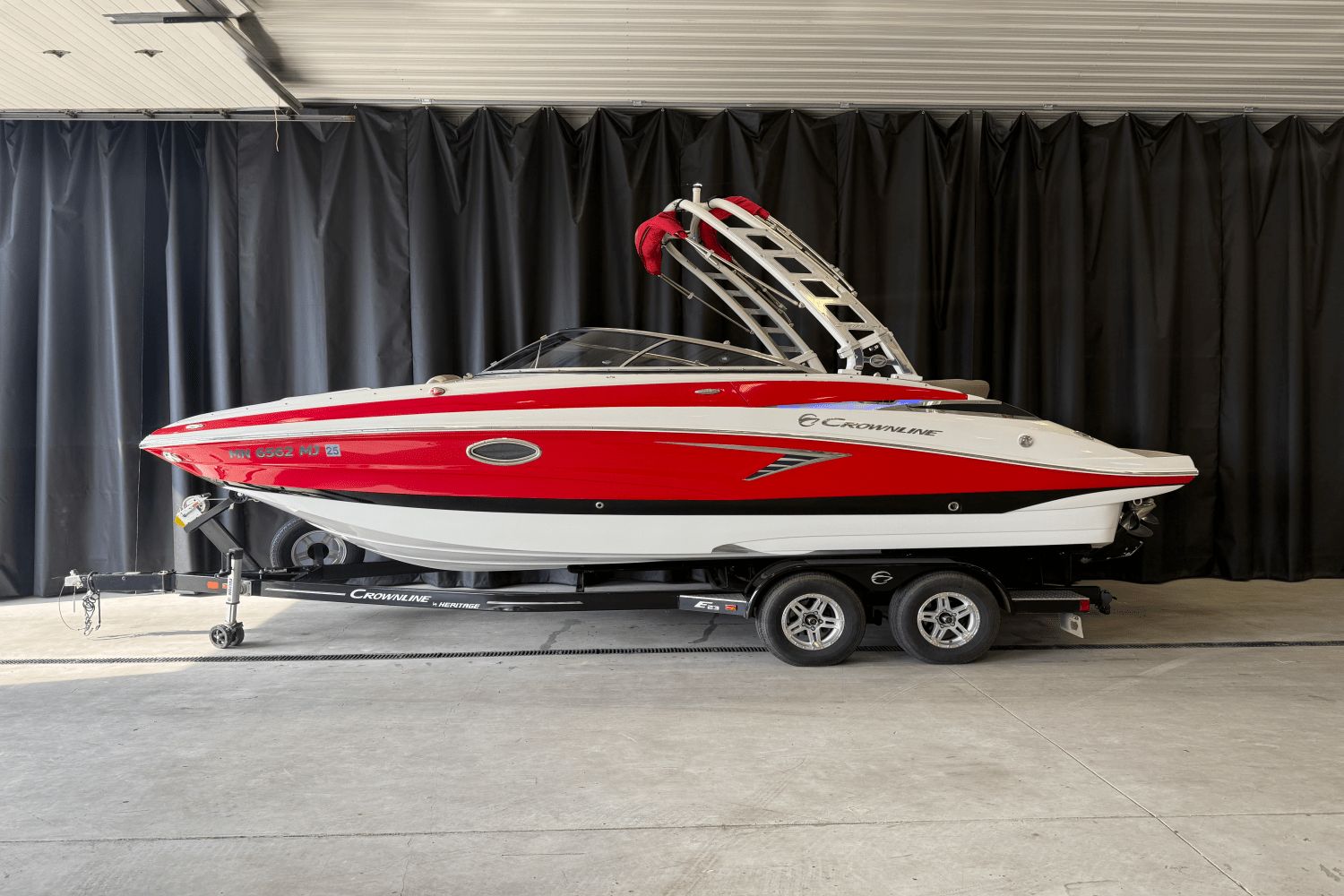 Crownline E23 2018 Crownline E23 boat in red and white on a trailer indoors.