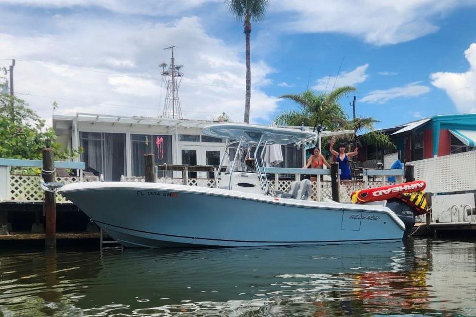 Release 240 RX 2019 Release 240 RX boat docked near waterfront home with palm trees.