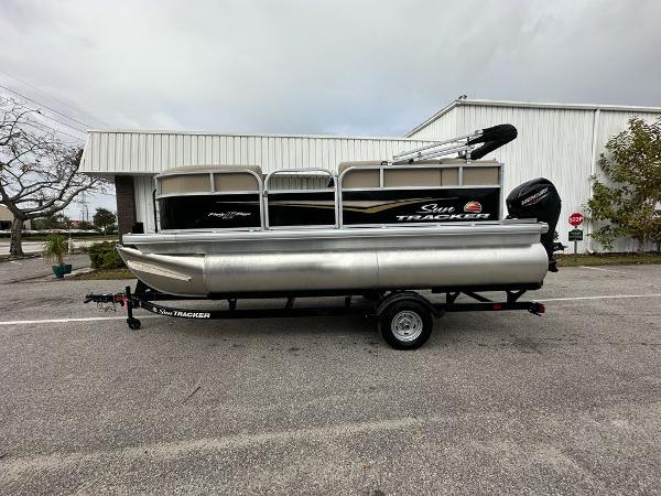 Sun Tracker Party Barge 16 DLX 2025 Sun Tracker Party Barge 16 DLX pontoon boat on trailer, parked outdoors.