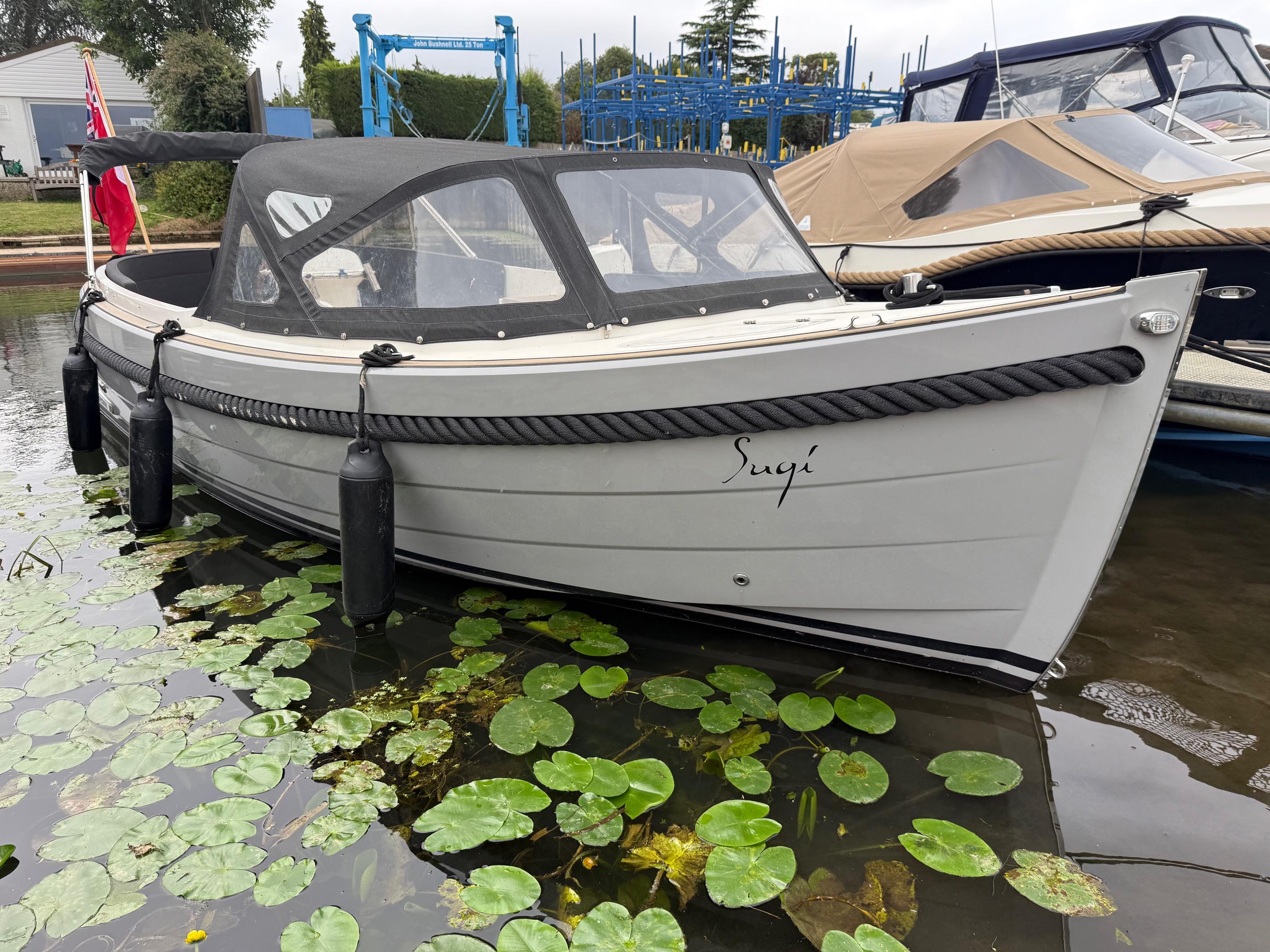 Maril 6 NXT 2021 Maril 6 NXT boat docked, surrounded by lily pads, with a black canopy.