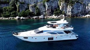 Azimut 78 Luxurious 2013 Azimut 78 yacht cruising near rocky coastline, surrounded by clear blue water.