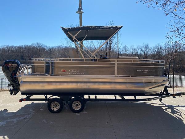 Sun Tracker Fishin' Barge 20 DLX 2025 Sun Tracker Fishin' Barge 20 DLX pontoon boat on trailer, parked outdoors.