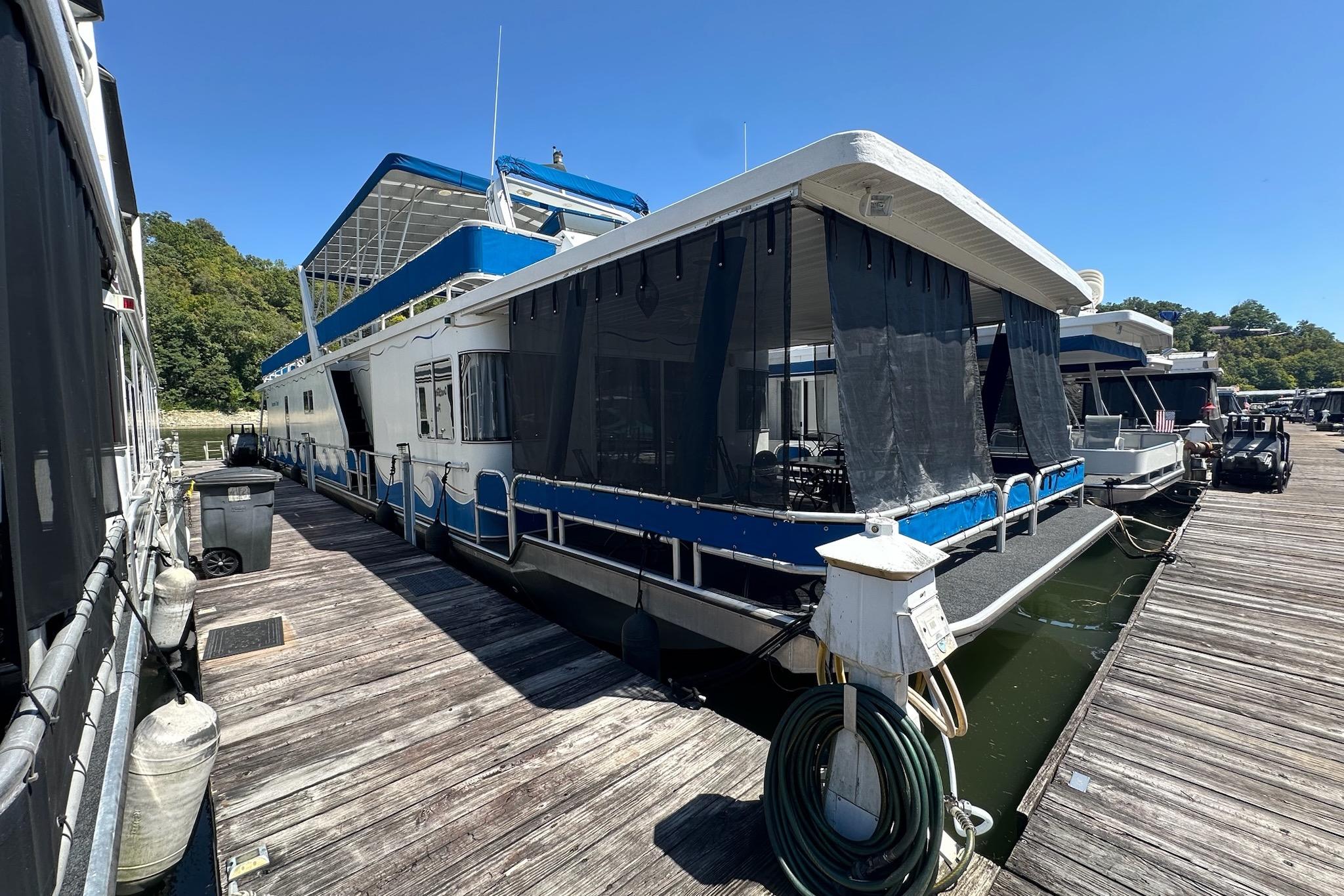 Jamestowner 16x78 2002 Jamestowner houseboat docked, featuring blue and white design with covered deck area.