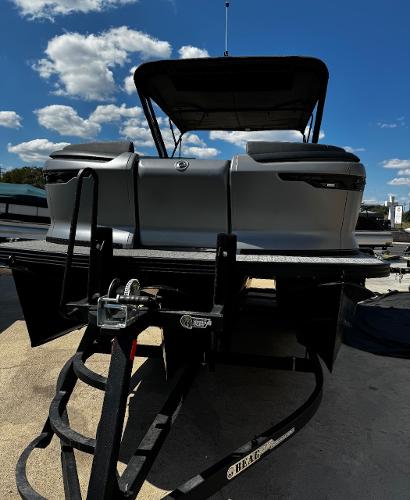Manitou Explore 2024 Manitou Explore boat on trailer under blue sky.