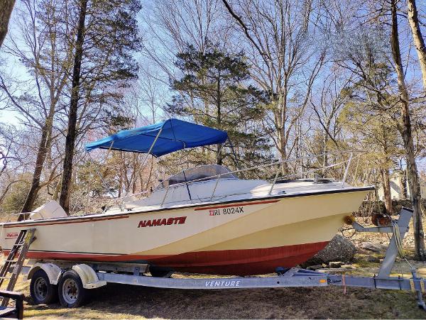 Boston Whaler 25 Revenge 1983 Boston Whaler 25 Revenge boat on trailer with blue canopy in wooded area.