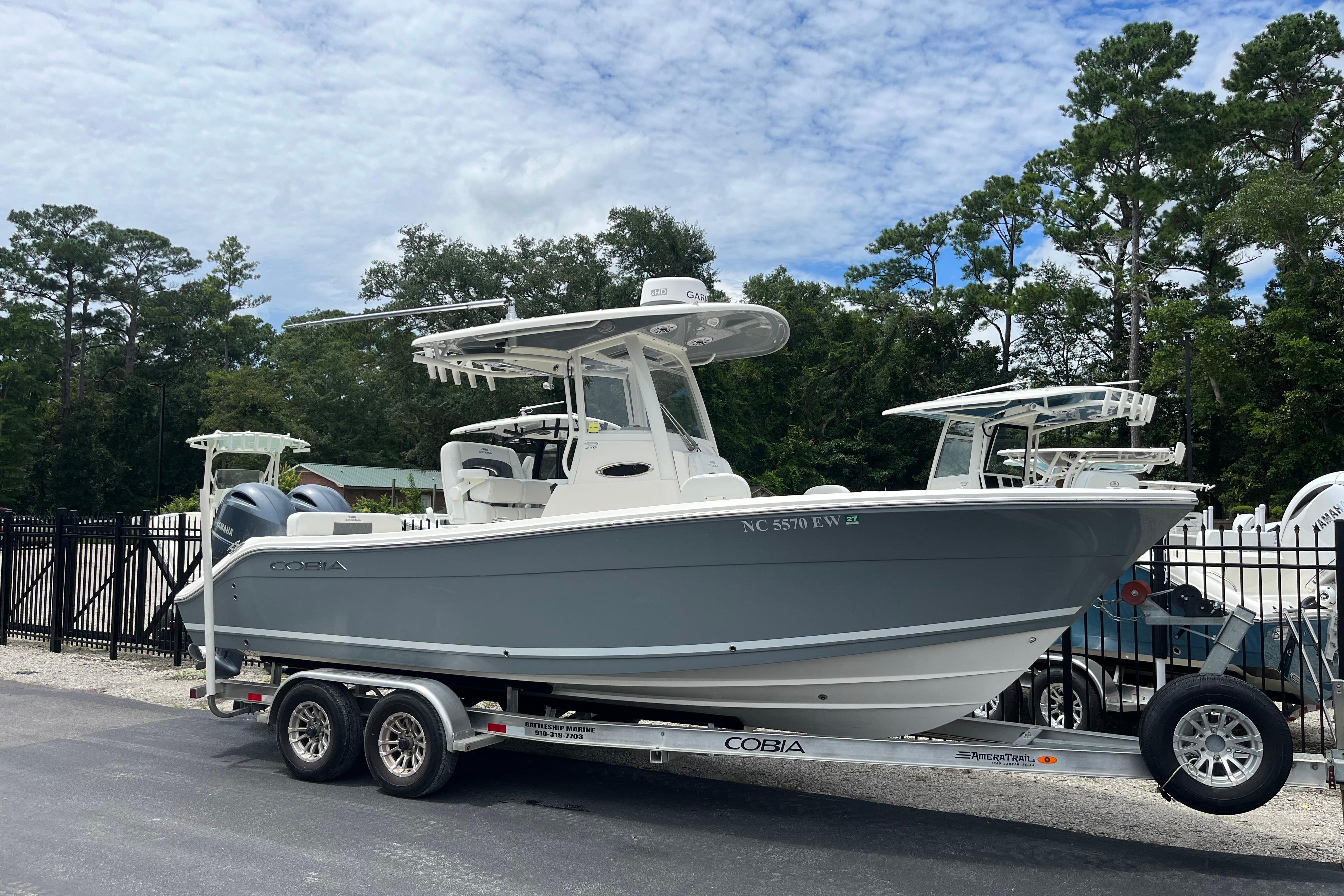 Cobia 240 Center Console 2022 Cobia 240 Center Console boat on trailer, parked outdoors with trees in background.