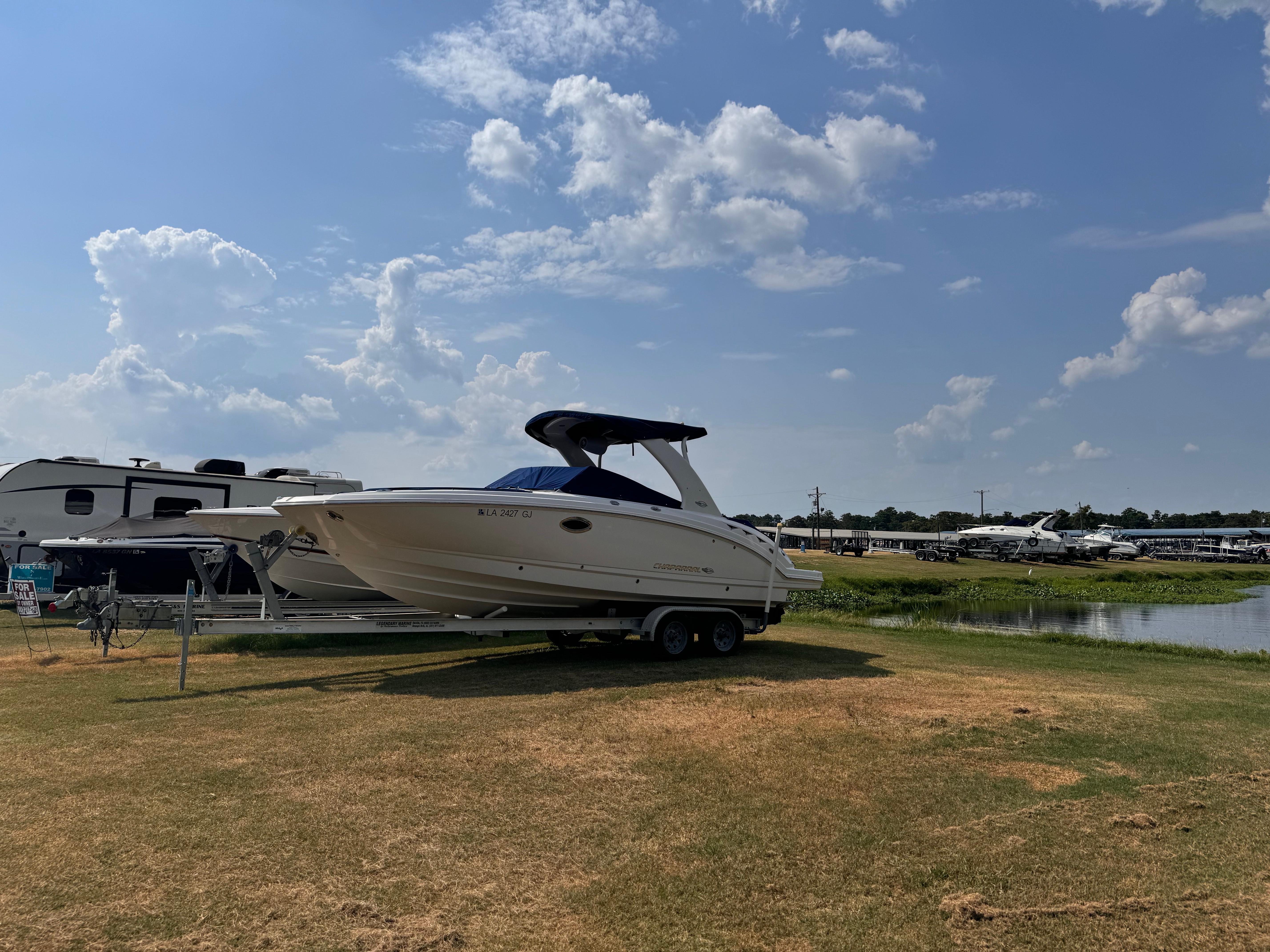 Chaparral 264 Sunesta 2012 Chaparral 264 Sunesta boat on trailer, parked near RVs by a lake.