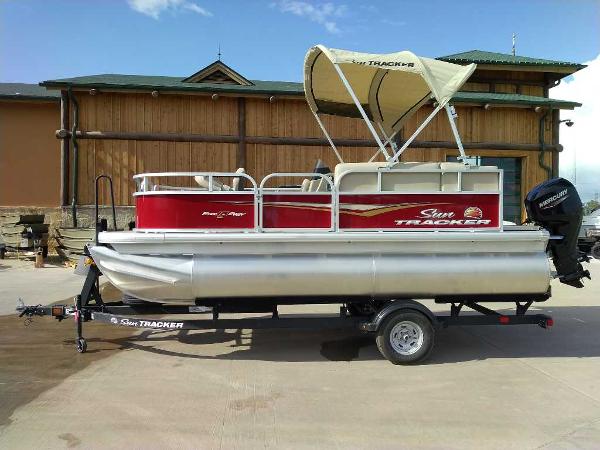 Sun Tracker Bass Buggy 16 XL Select 2025 Sun Tracker Bass Buggy 16 XL Select pontoon boat on trailer, parked outdoors.