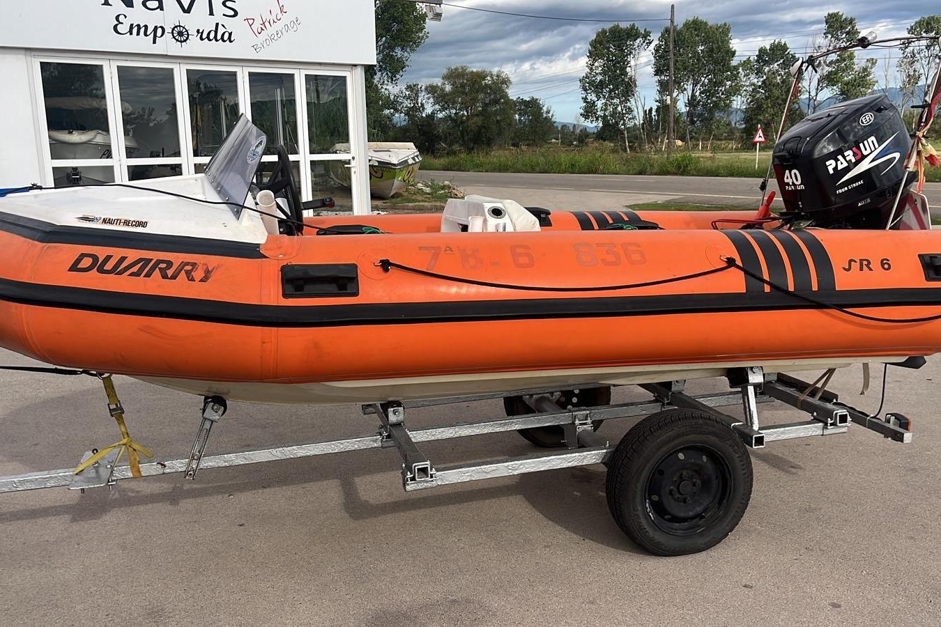 Duarry SR 6 Orange 1981 Duarry SR 6 inflatable boat on trailer, parked near a building.