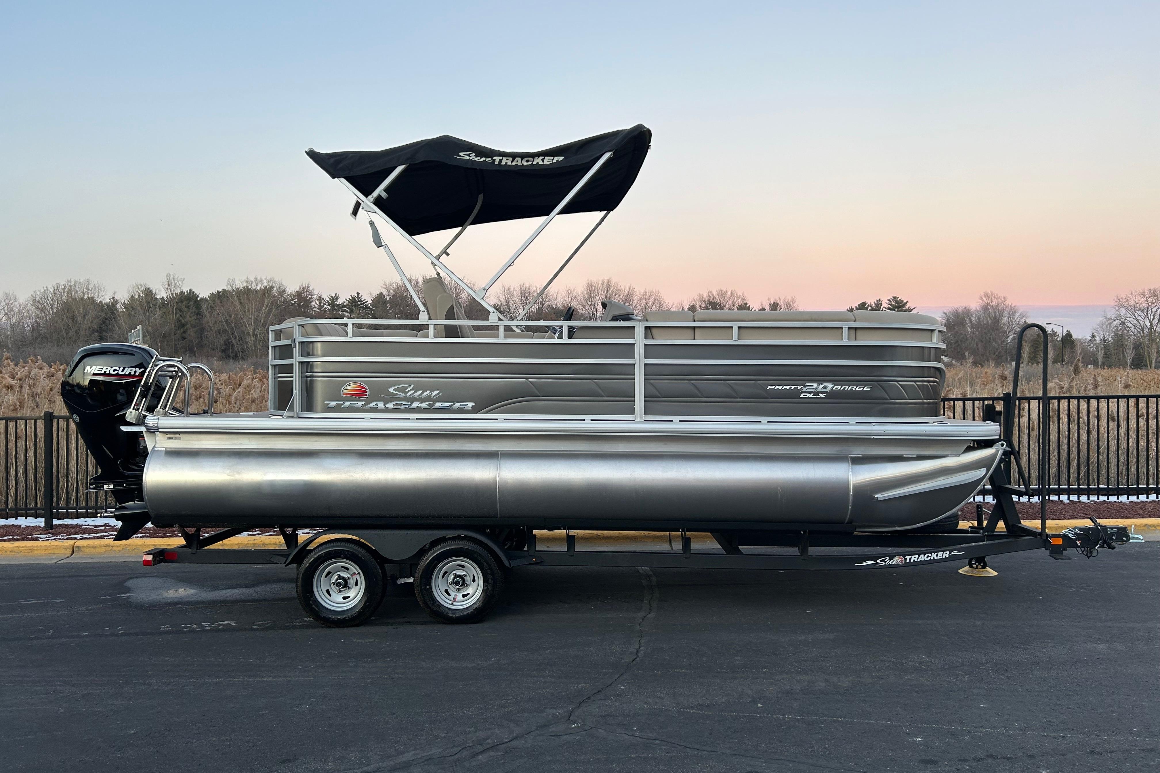 Sun Tracker Party Barge 20 DLX 2025 Sun Tracker Party Barge 20 DLX pontoon boat on trailer at sunset.