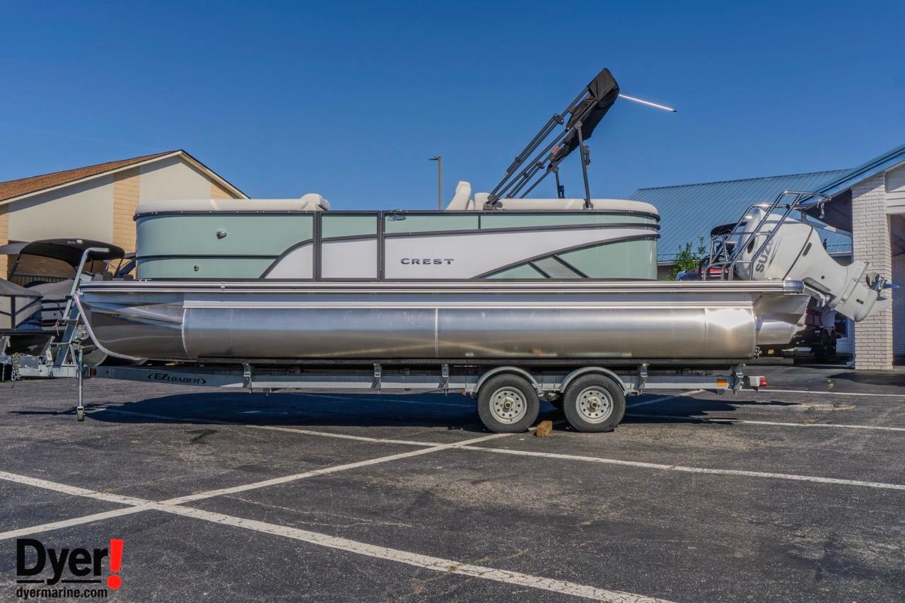 Crest Conquest 230 SLC 2026 Crest Conquest 230 SLC pontoon boat on trailer in parking lot.
